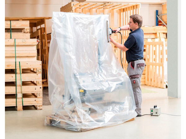 Die Folienschweißzange SZ wird von einem Mann gehalten und Schweißt eine Folie zusammen in der eine Maschine steht.