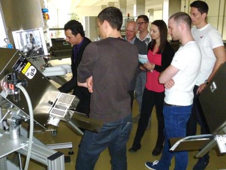 Eine Gruppe von Menschen schaut sich eine Verpackungsmaschine an.