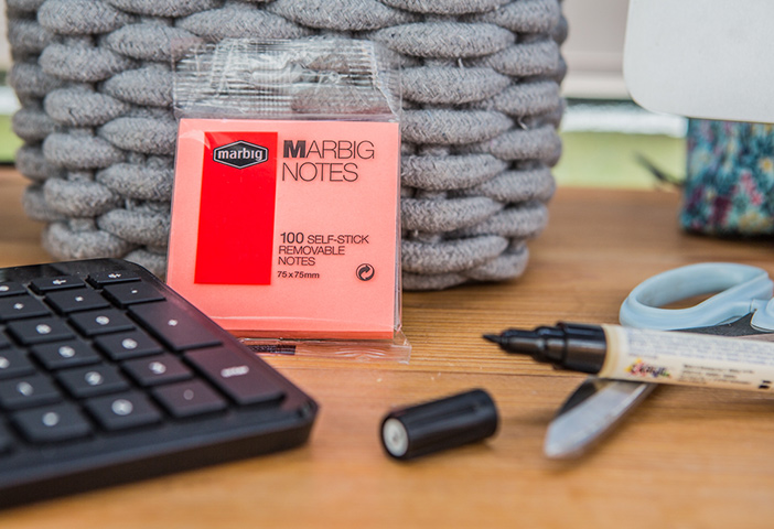 Eine Tastatur ein, offener Permanentmarker, eine Schere und ein Block mit Abreisbaren Zetteln liegen auf einem Tisch.