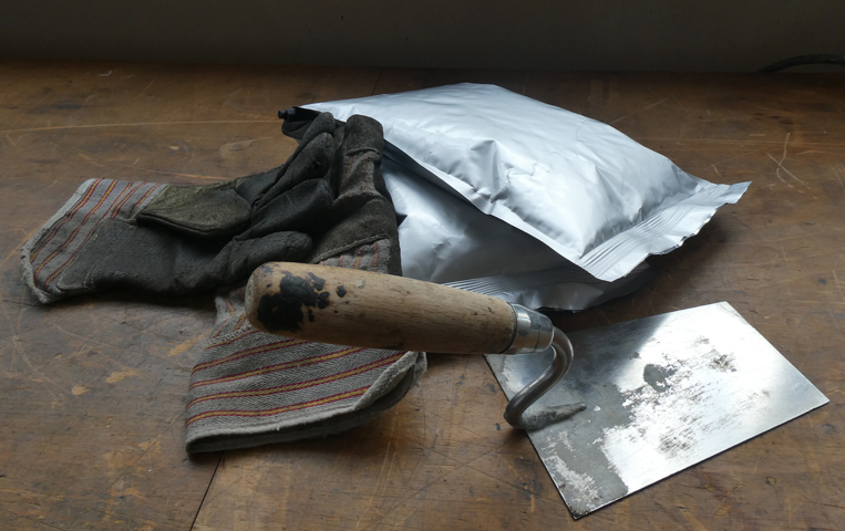 Doppelkammerbeutel mit Arbeitshandschuhen und Maurerkelle