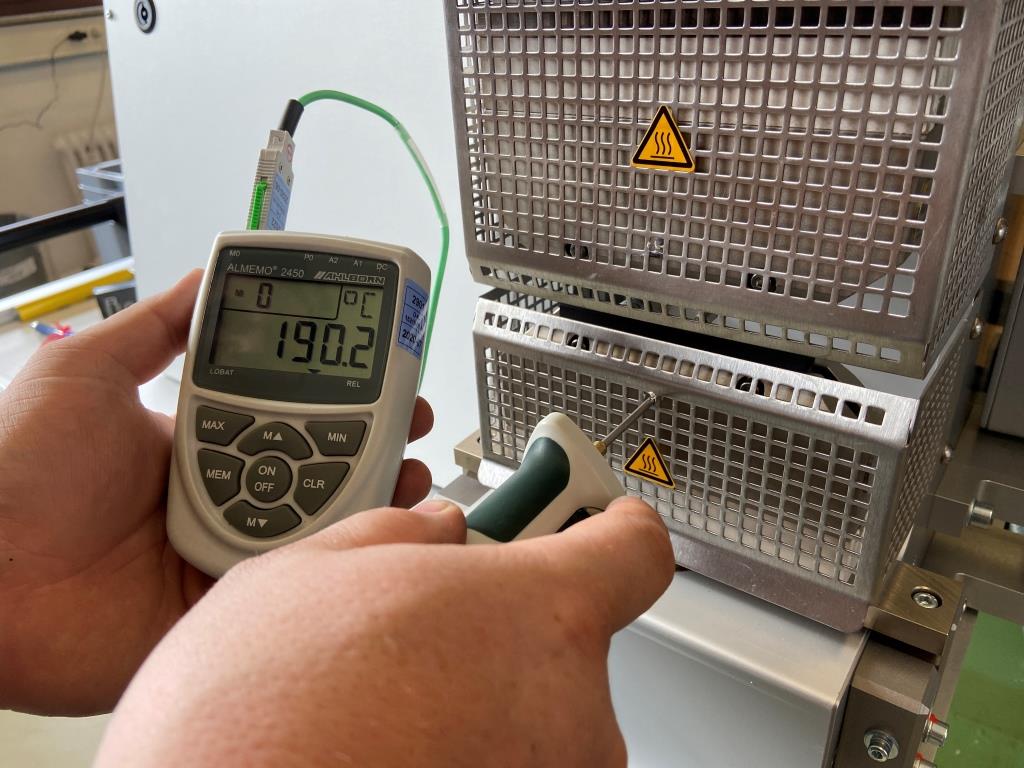 Ein Kontrollmessgerätgerät wird zur Messung der Temperatur durch ein Lochblech geschoben. Es zeigt 190,2°C an.