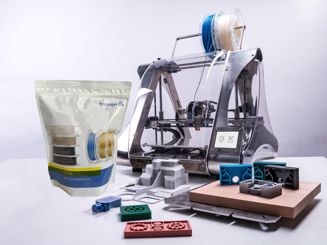 Eine Verpackung von Fäden steht rechts im Bild, im Vordergrund sind Bausteine und im Hintergrund steht eine Nähmaschine.