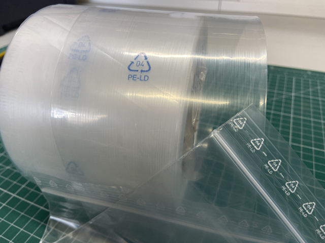 Folienrolle aus PE-LD mit einem Recyclingcode. Im Vordergrund ist ein Druckverschlussbeutel zu sehen, auf dem ebenfalls Recyclingcodes gedruckt sind.