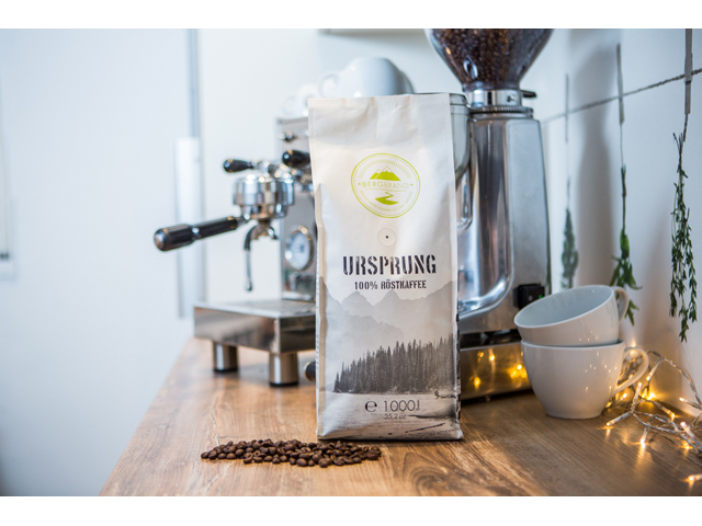 EIn Kaffeebeutel und zwei Kaffeetassen stehen vor einer Kaffeemaschine.